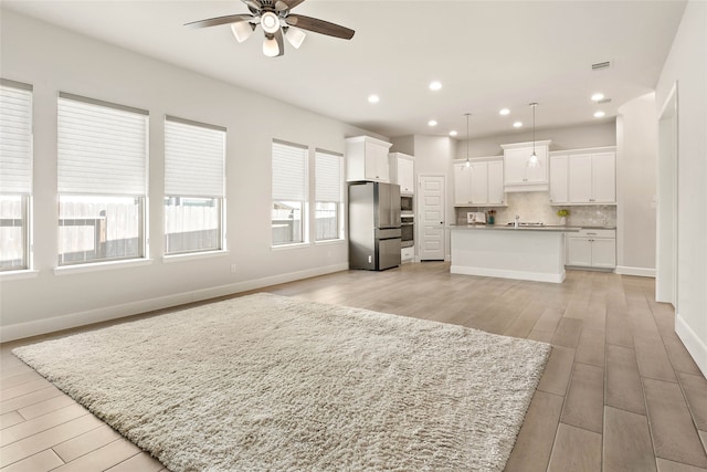 kitchen featuring open floor plan, backsplash, stainless steel appliances, and a ceiling fan