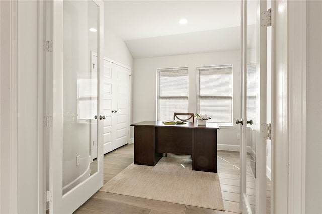 office area with light wood finished floors, baseboards, and lofted ceiling