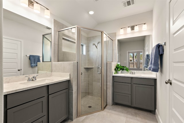 bathroom featuring a shower stall, two vanities, visible vents, and a sink