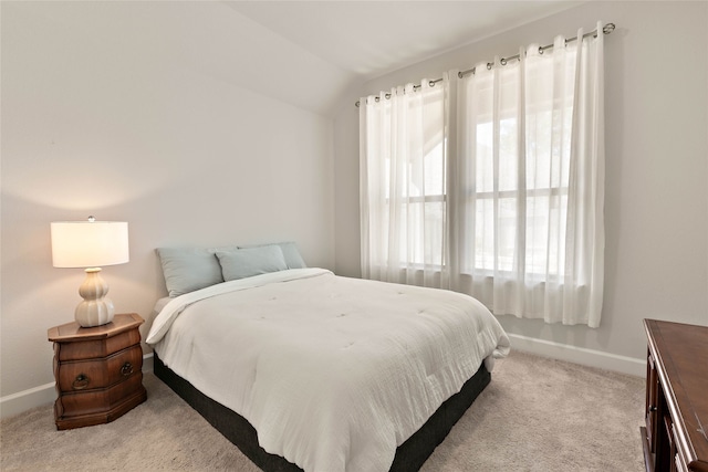 bedroom with lofted ceiling, light colored carpet, and baseboards