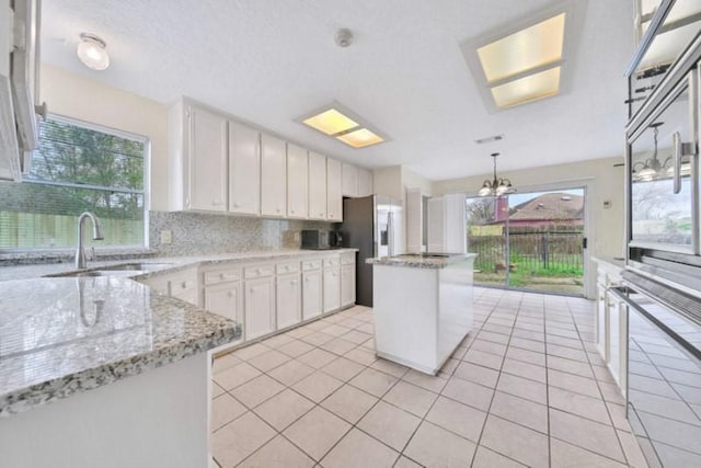 kitchen with a sink, decorative backsplash, a center island, and white cabinetry