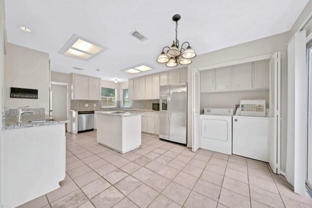 kitchen with visible vents, washer and clothes dryer, tasteful backsplash, an inviting chandelier, and appliances with stainless steel finishes