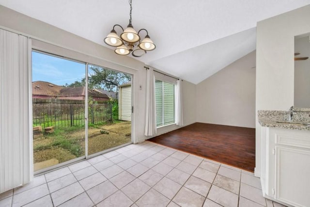 doorway to outside with vaulted ceiling, a notable chandelier, light tile patterned floors, and a sink