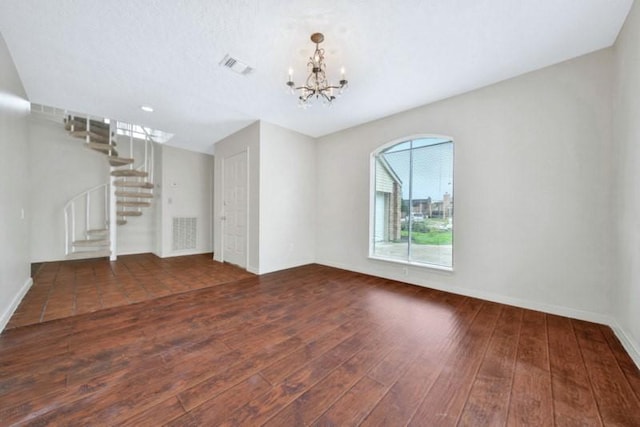 unfurnished living room featuring stairway, an inviting chandelier, hardwood / wood-style floors, and visible vents