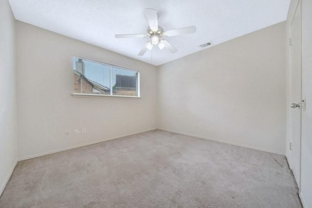 empty room featuring carpet flooring, a ceiling fan, visible vents, and baseboards