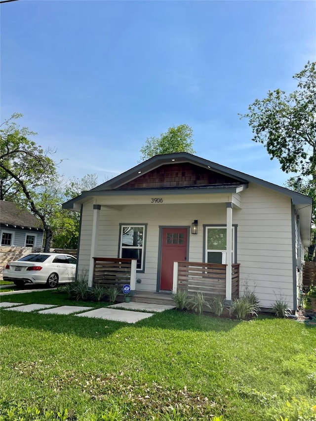 bungalow-style home with a front yard and covered porch