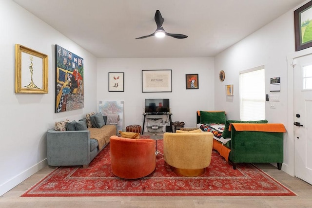 living area featuring baseboards and a ceiling fan