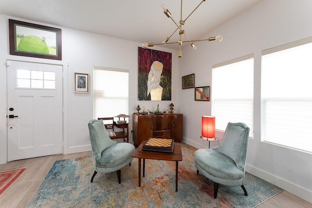 sitting room with a chandelier, baseboards, and wood finished floors