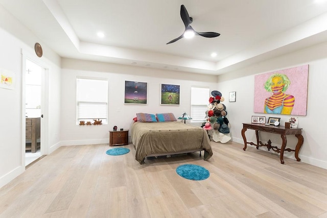 bedroom featuring a raised ceiling, recessed lighting, light wood-style floors, and baseboards