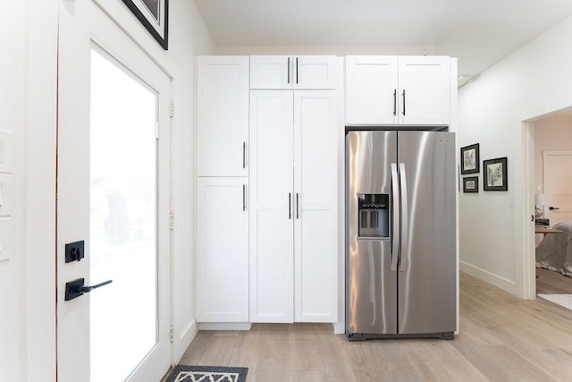 kitchen featuring white cabinetry, stainless steel fridge with ice dispenser, baseboards, and light wood finished floors