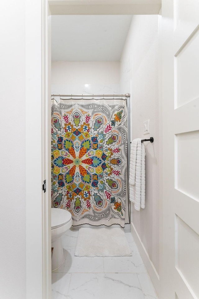 bathroom with a shower with curtain, marble finish floor, toilet, and baseboards