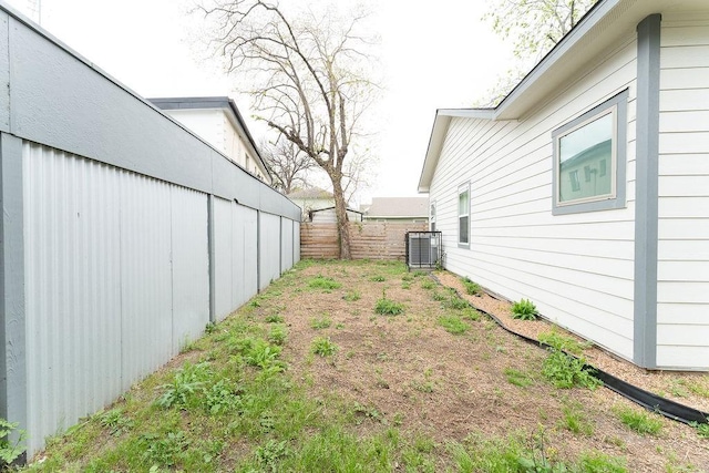 view of yard featuring fence and central AC