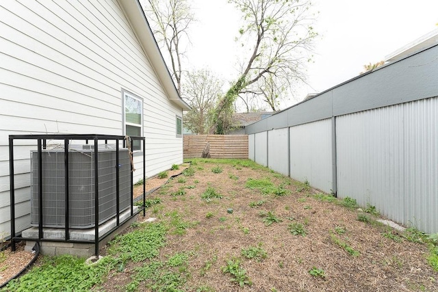 view of yard featuring central AC unit and fence