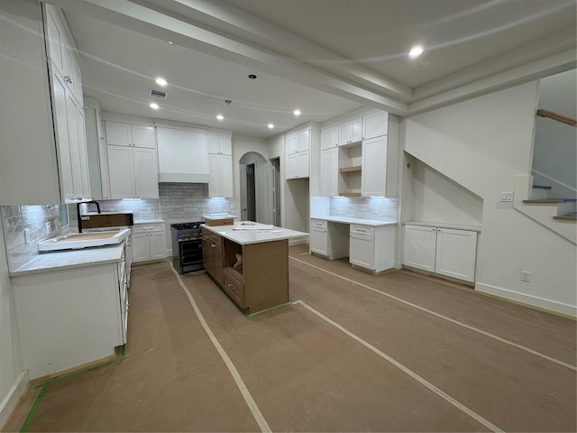 4403 Feagan, Houston, TX 77007 - kitchen with backsplash, premium range hood, gas stove, arched walkways, and white cabinetry