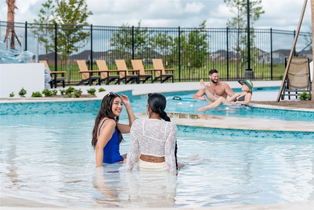 view of swimming pool featuring fence and a water play area