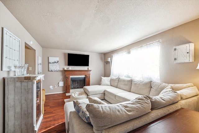 living area with baseboards, a fireplace, dark wood-type flooring, a textured ceiling, and a textured wall