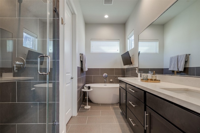 bathroom with tile patterned floors, a freestanding bath, a stall shower, and double vanity