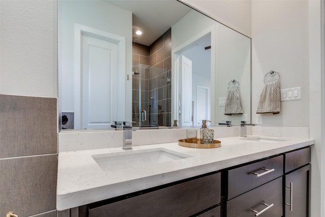 bathroom with double vanity, a stall shower, and a sink