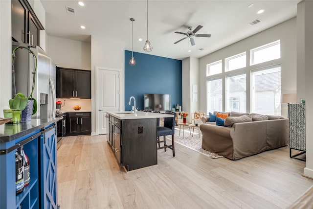 kitchen with open floor plan, a kitchen bar, a ceiling fan, and a sink