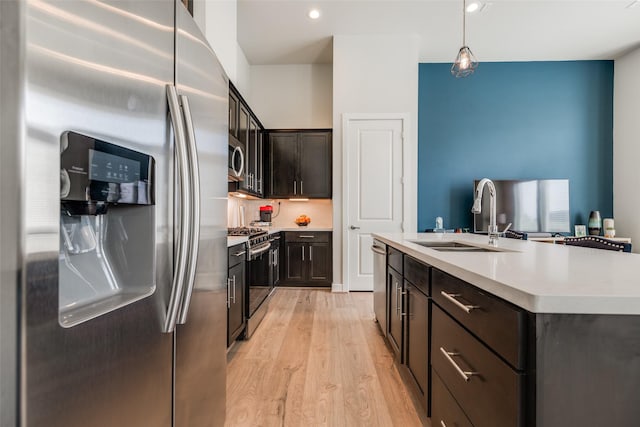 kitchen with light wood-type flooring, a sink, dark brown cabinetry, appliances with stainless steel finishes, and light countertops