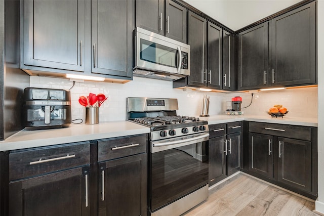 kitchen with decorative backsplash, light wood-style flooring, stainless steel appliances, and light countertops