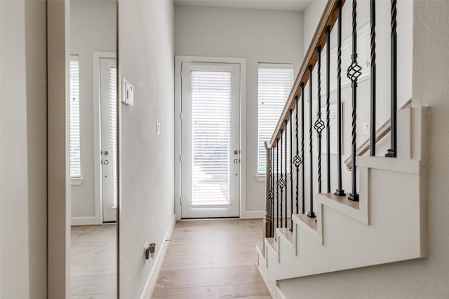 foyer featuring stairway, light wood-type flooring, and baseboards