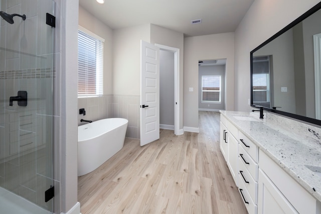 full bathroom with visible vents, a shower stall, a freestanding tub, wood finished floors, and vanity