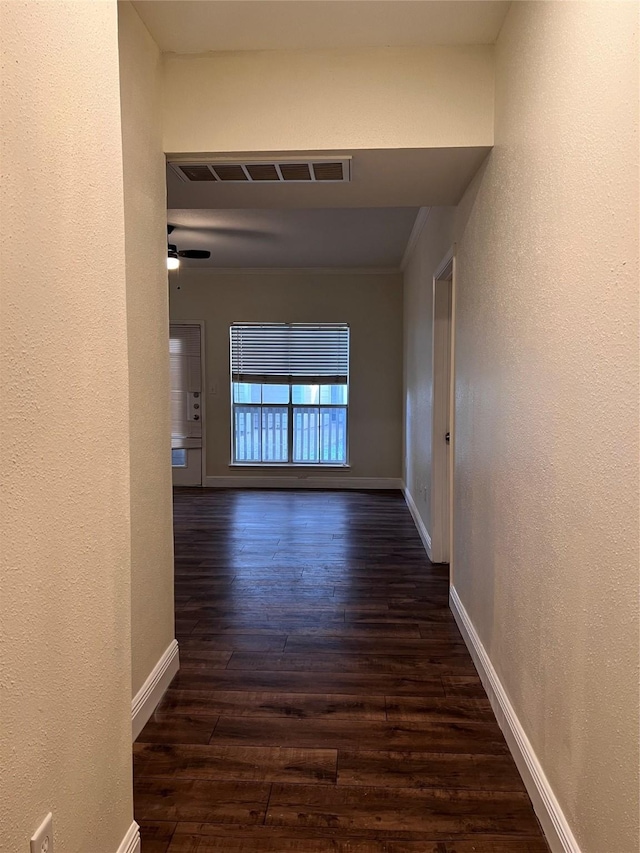 corridor with visible vents, baseboards, dark wood finished floors, and a textured wall