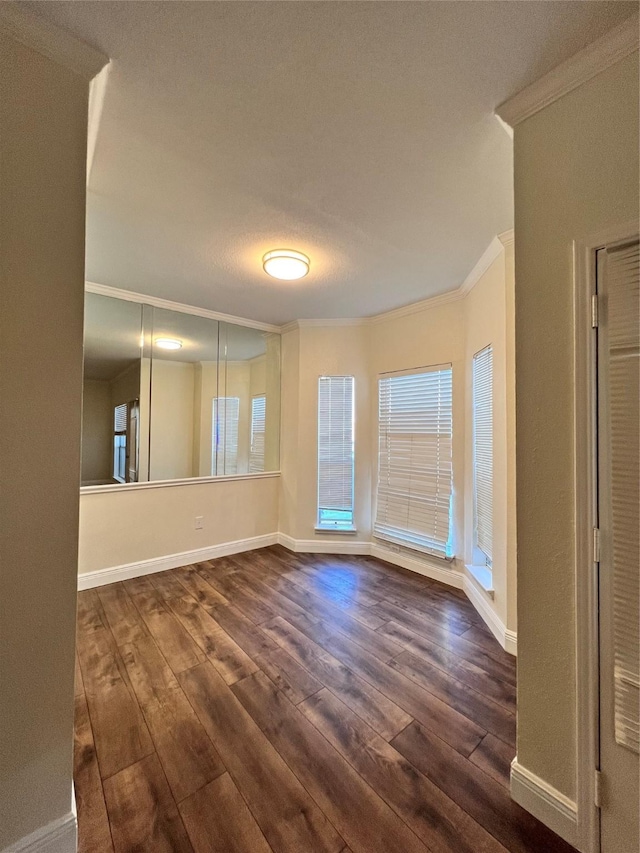 unfurnished room with dark wood finished floors, crown molding, and baseboards