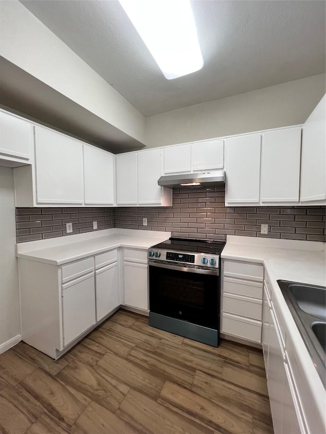 kitchen with decorative backsplash, stainless steel range with electric cooktop, white cabinetry, and extractor fan