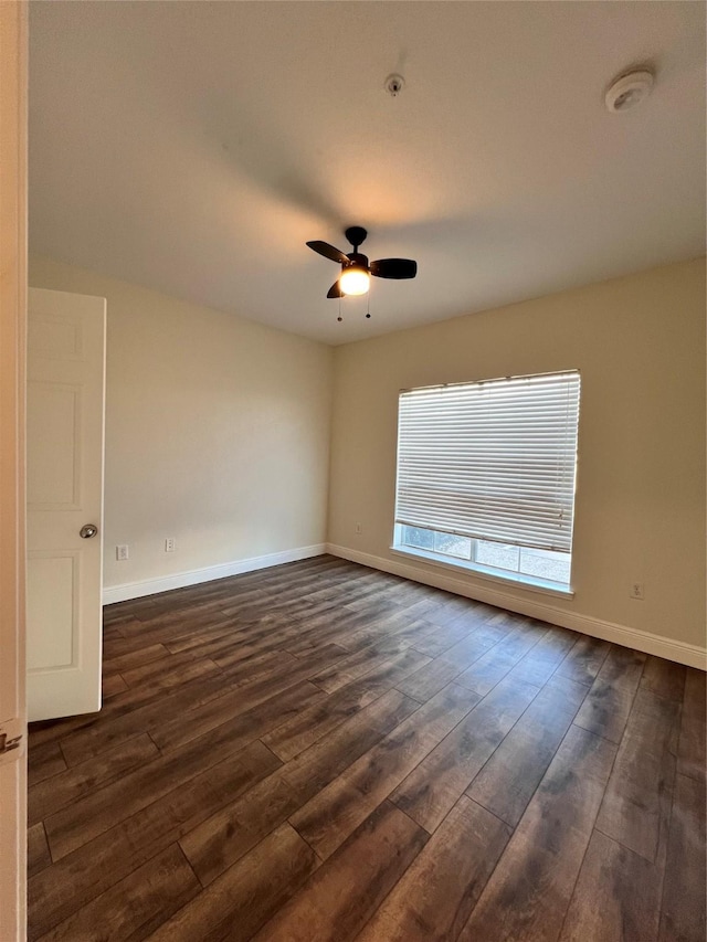 unfurnished room featuring baseboards, dark wood-type flooring, and a ceiling fan