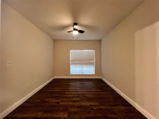 empty room with baseboards, a ceiling fan, and dark wood-style flooring