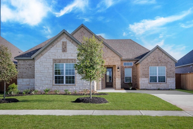 view of front of property featuring a front lawn, brick siding, stone siding, and a shingled roof