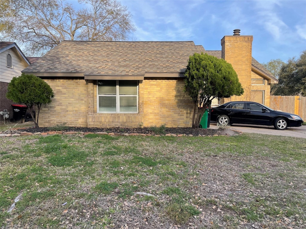 view of side of home featuring brick siding, a chimney, and a shingled roof