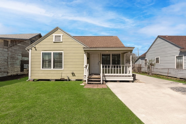 view of front facade with roof with shingles, a porch, concrete driveway, and a front lawn