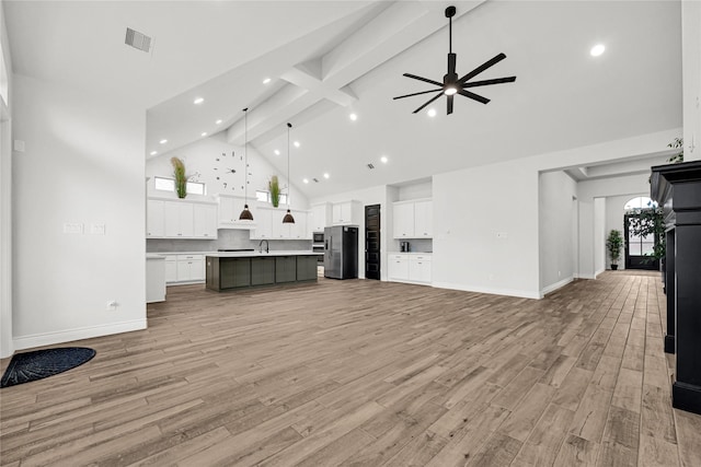 unfurnished living room featuring baseboards, visible vents, high vaulted ceiling, beam ceiling, and light wood-style floors