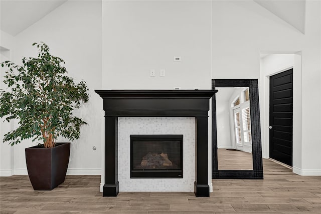 interior details with a tiled fireplace, wood finished floors, and baseboards