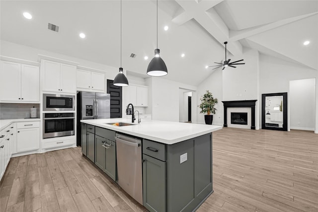 kitchen featuring white cabinets, appliances with stainless steel finishes, light wood-style floors, and a sink