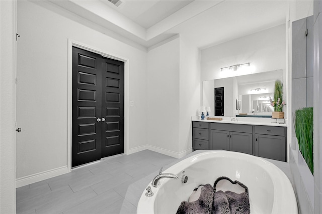 full bathroom featuring vanity, visible vents, a tub with jets, and baseboards