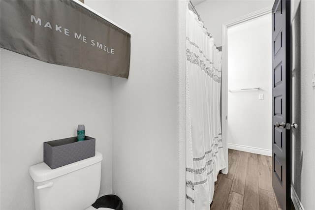 full bathroom featuring baseboards, toilet, and wood finished floors