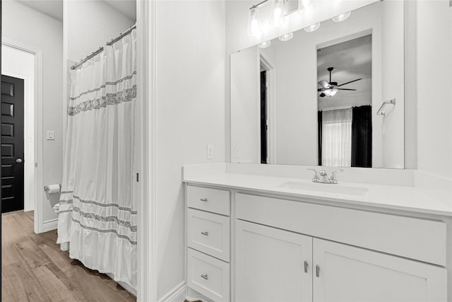 full bath featuring baseboards, vanity, ceiling fan, and wood finished floors