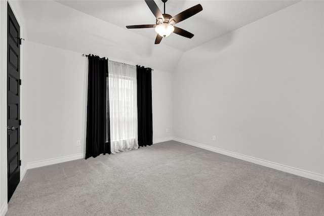 empty room with vaulted ceiling, carpet flooring, baseboards, and ceiling fan