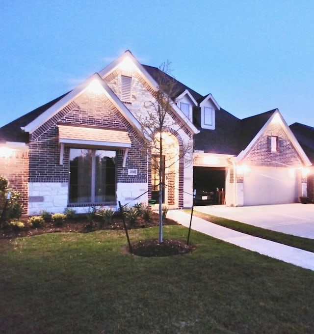 view of front of house featuring stone siding, a garage, driveway, and a front lawn