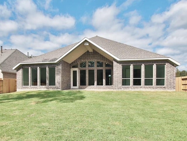 back of property featuring brick siding, a lawn, a fenced backyard, and roof with shingles