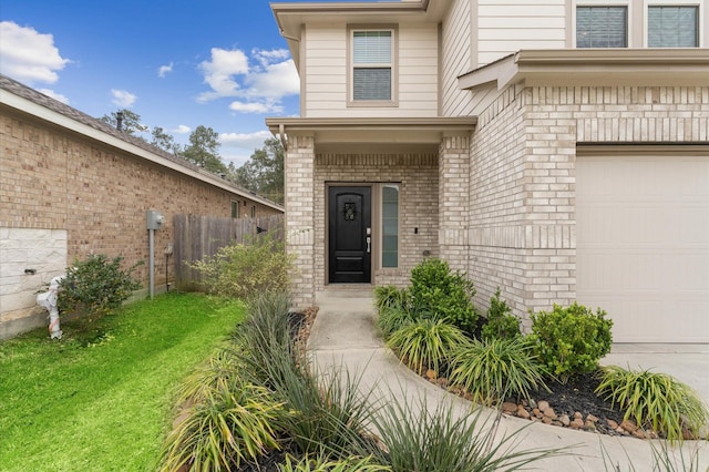 entrance to property with a garage, fence, brick siding, and a lawn