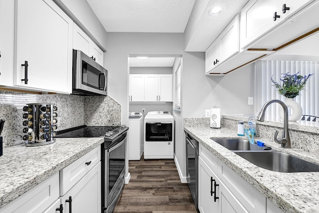 kitchen with dark wood-style flooring, a sink, stainless steel appliances, independent washer and dryer, and backsplash