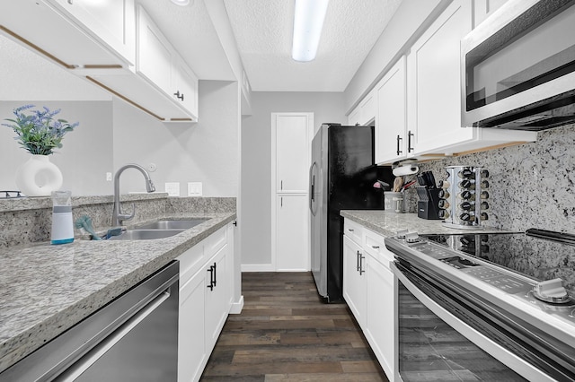 kitchen featuring a sink, stainless steel appliances, light stone counters, and dark wood-style flooring