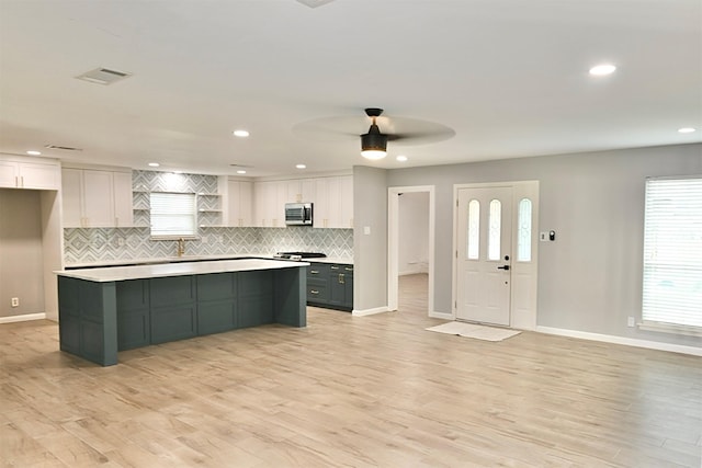 kitchen with stainless steel microwave, white cabinets, a center island, and light countertops