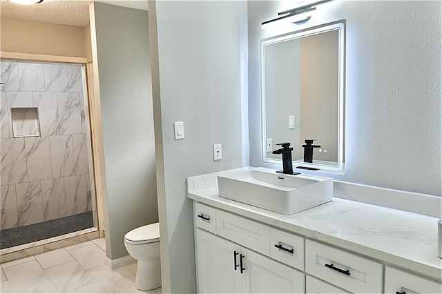 full bathroom with a stall shower, toilet, vanity, and a textured ceiling