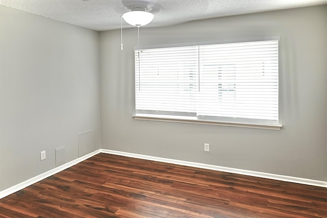 empty room with plenty of natural light, wood finished floors, baseboards, and a textured ceiling